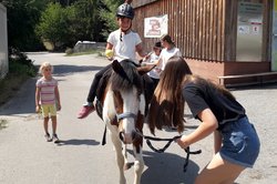 Junge Frau führt Pferd mit Kind