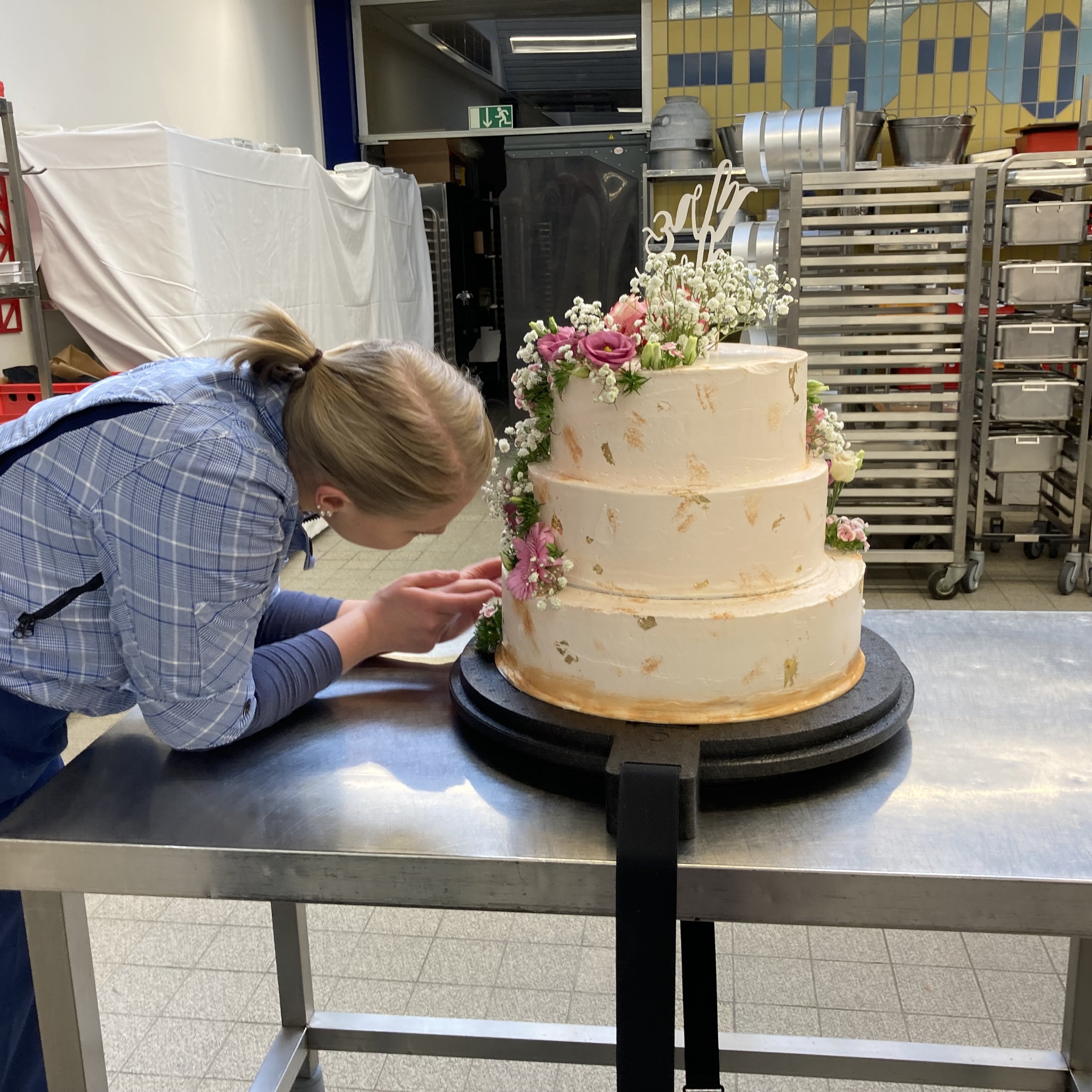 Eine Konditorin arbeitet an einer dreistöckigen Torte.