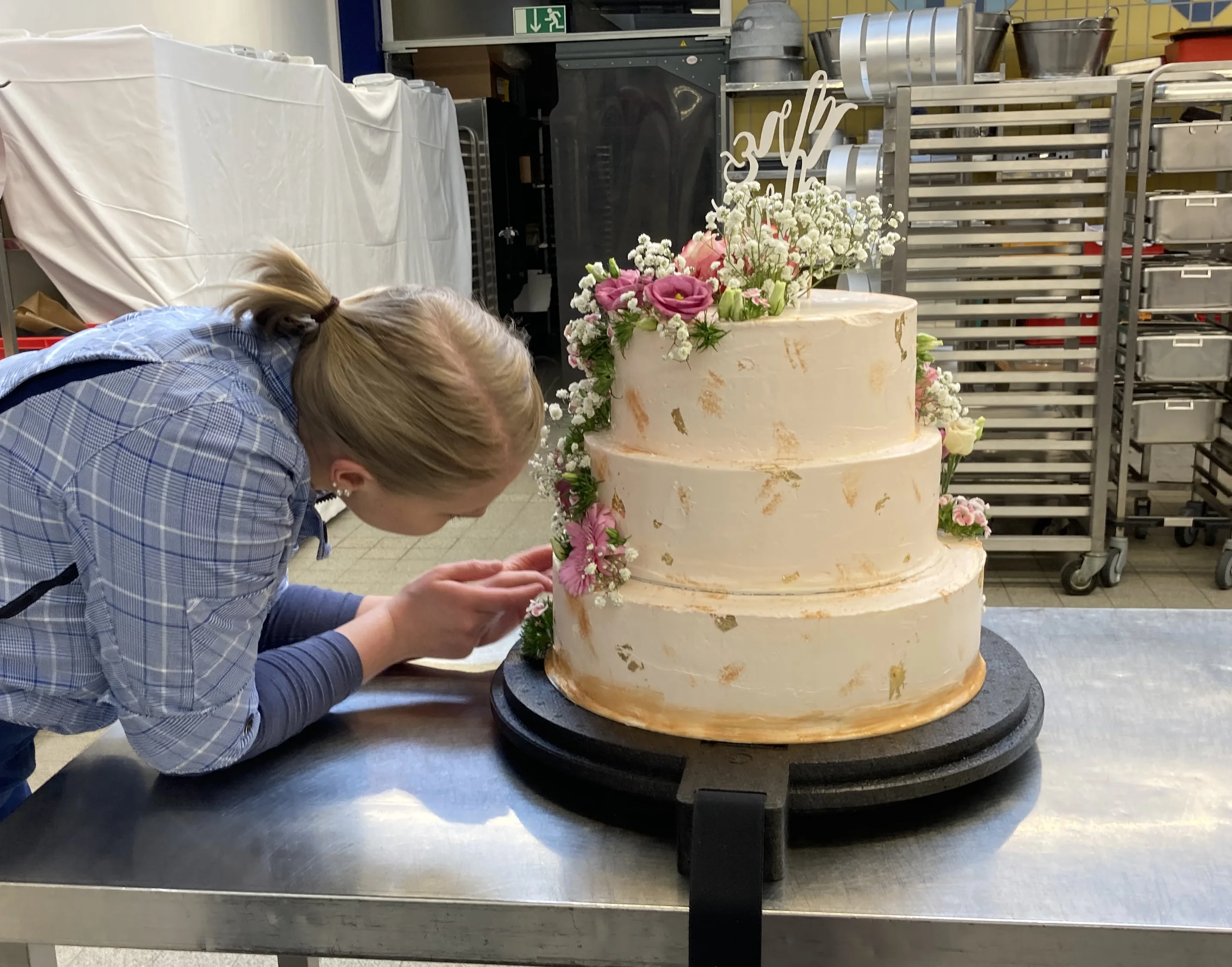 Eine Konditorin arbeitet an einer dreistöckigen Torte.