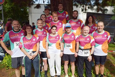 Eine Gruppe von Sportlerinnen und Sportlern in einheitlichen Sportshirts der Johannes-Diakonie lächelt in die Kamera.