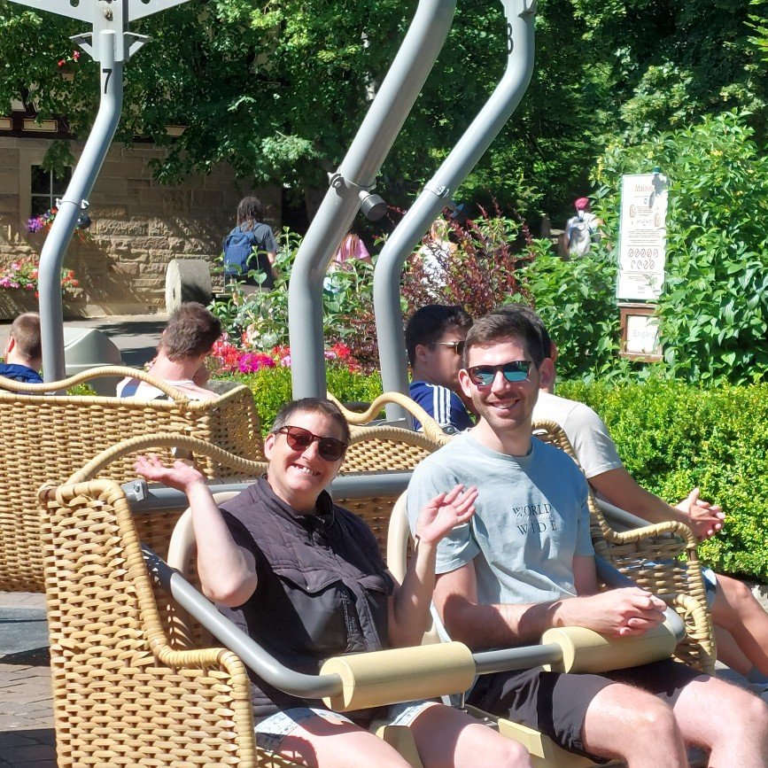 Ein junger Mann und eine Frau sitzen in einem Fahrgeschäft in einem Freizeitpark.