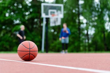 Ein Basketball liegt auf einem Basketballplatz.