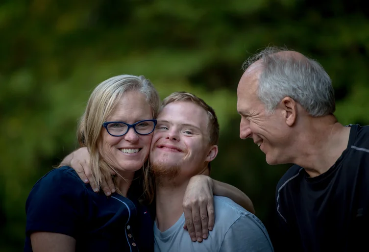 Eine Familie mit Mann, Frau und Sohn lachen. Die Mutter und der Sohn umarmen sich.