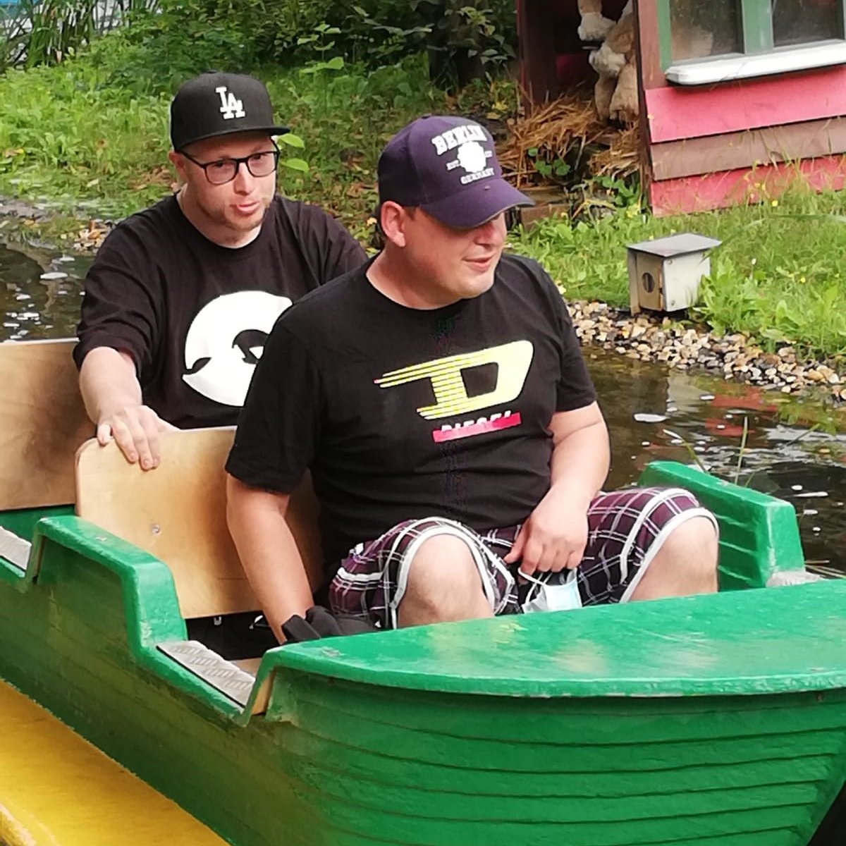 Zwei Männer sitzen in einem kleinen Boot in einem Freizeitpark.