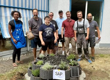 SAP-Mitarbeitende und Helfer stehen hinter einem neu gebauten Solarbrunnen.