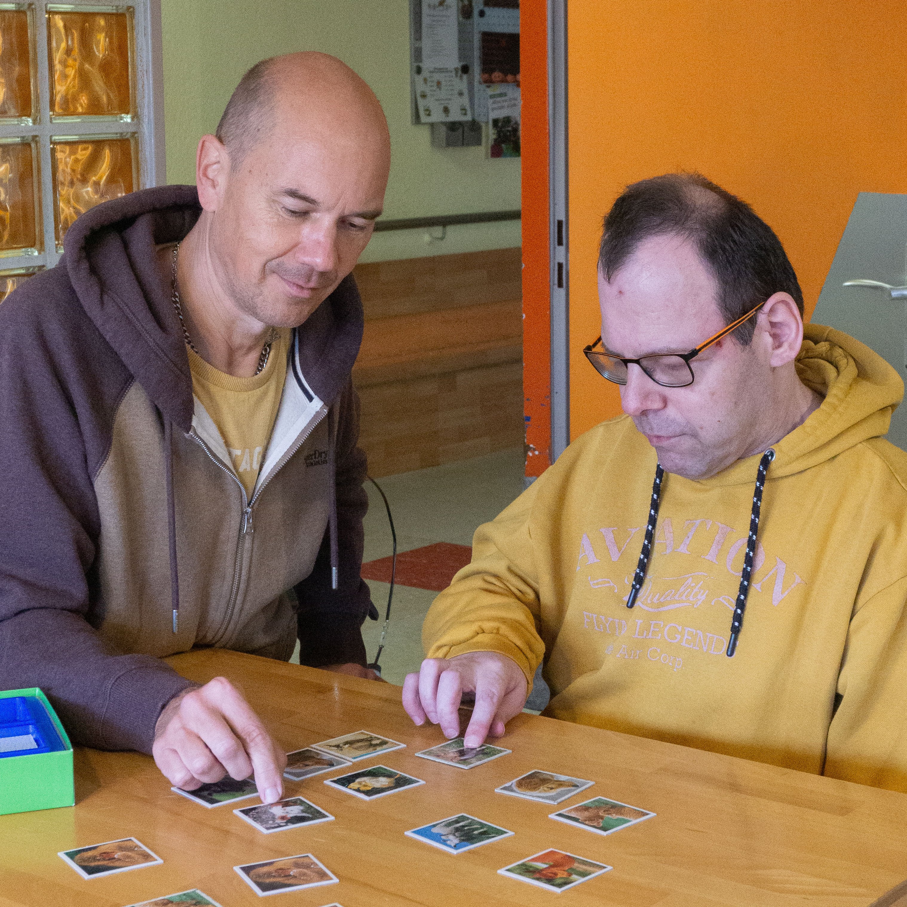 Zwei Männer sitzen an einem Tisch und machen ein Puzzle.