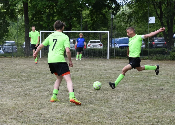 Männer spielen Fußball auf einem Fußballplatz, einer holt gerade zum Schuss aus.