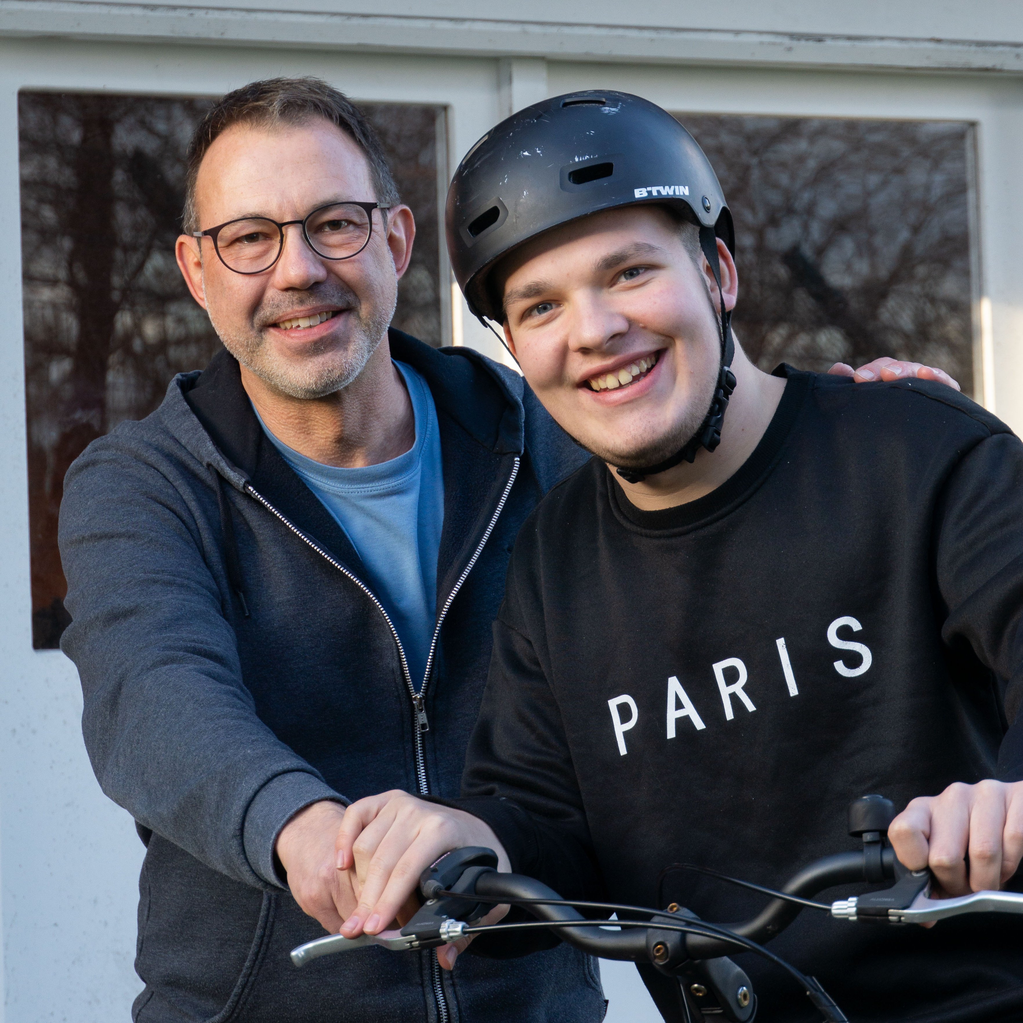 Ein Mitarbeiter unterstützt einen Jugendlichen auf dem Fahrrad.