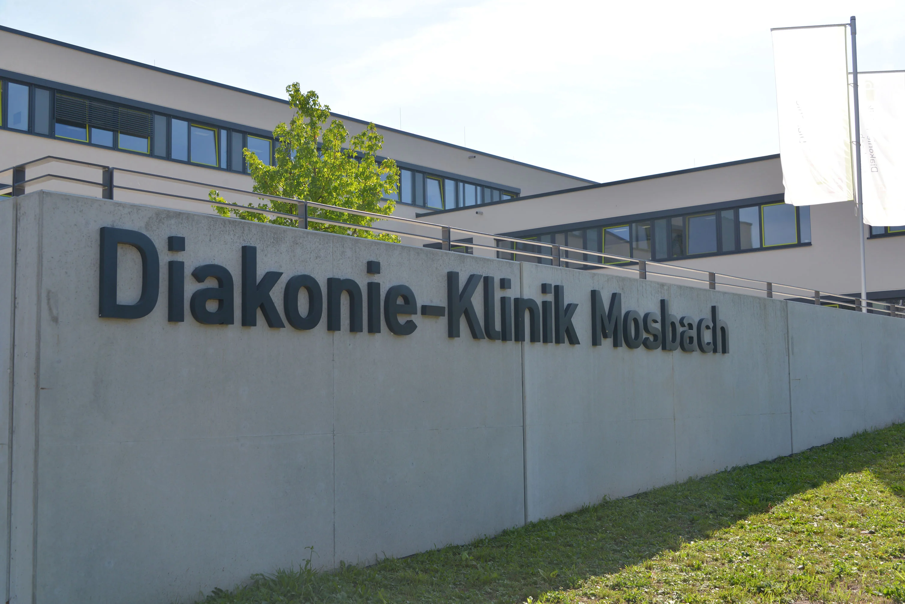 Eine Mauer auf der Diakonie-Klinik Mosbach steht, im Hintergrund ist das Gebäude zu sehen.