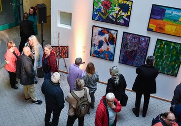 Besucher betrachten Bilder der Ausstellung "Ich WÜRDE gerne..."
