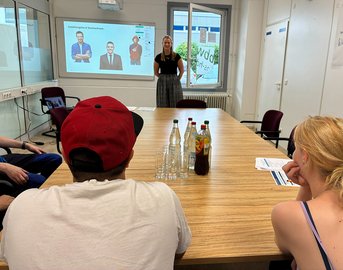 Trainerin präsentiert Auszubildenden in einem Seminarraum Tipps für Bewerbungsgespräche.