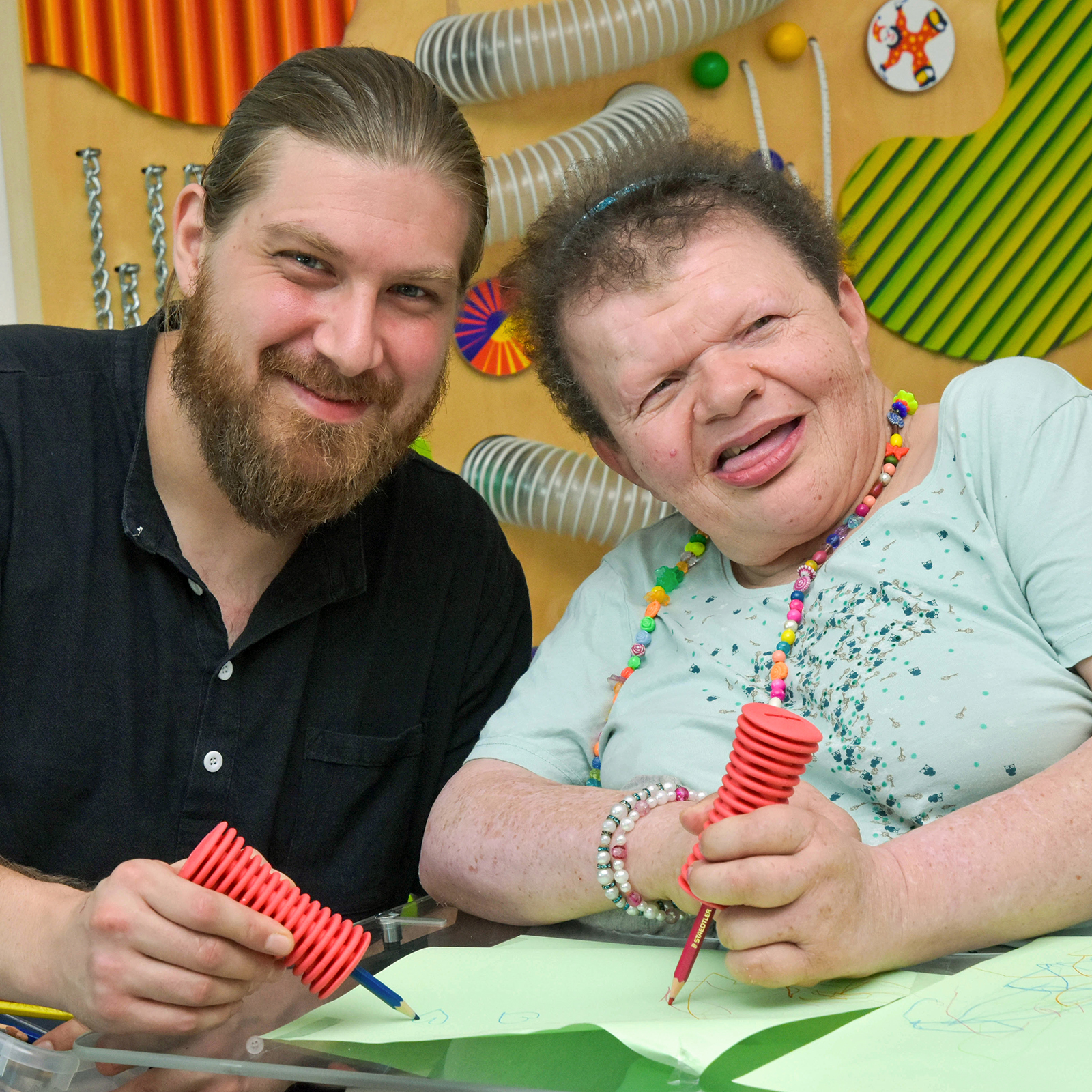 Assistent und Frau mit Behinderung malen gemeinsam