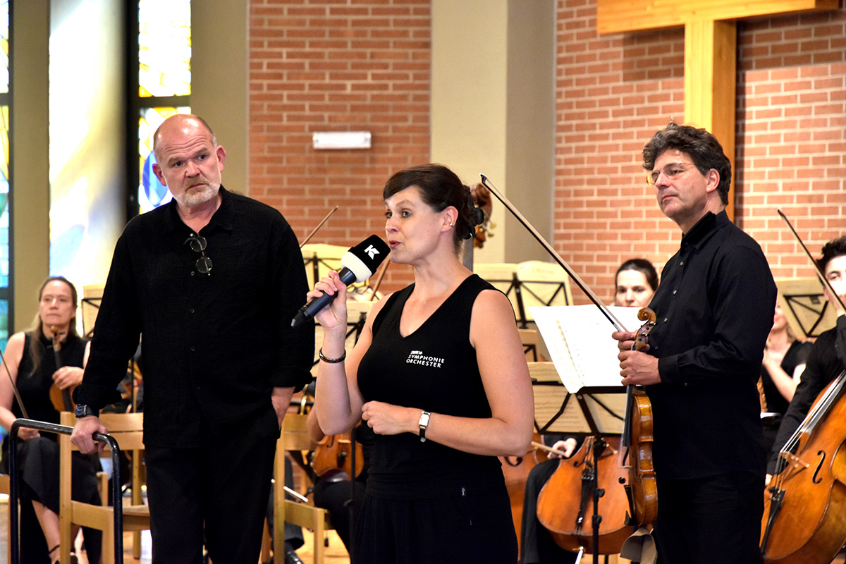 Chefdirigenten François-Xavier Roth und Moderatorin Jasmin Bachmann beim Konzert des SWR-Orchesters in der Johanneskirche