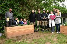 Menschen aus der Johannes-Diakonie stehen im Garten des Schulkindergartens Kleckse zwischen zwei neuen Hochbeeten.