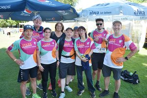 Eine Gruppe von 9 Männern und Frauen in einheitlichen Sportshirts lacht in die Kamera.