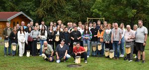 Eine Gruppe von rund 30 Männern und Frauen unterschiedlichen Alters stehen auf einer Wiese und lächeln in die Kamera.