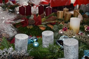 Auch selbstgefertigte Advents- und Weihnachtsdeko gehört zum Angebot der Märkte der Johannes-Diakonie. Adventskränze aus Tannenzweigen liegen auf einem Verkaufsstand. Die verschiedenen Kränze sind weihnachtlich geschmückt, unter anderem mit silbernen, goldenen, roten und weißen Kerzen.