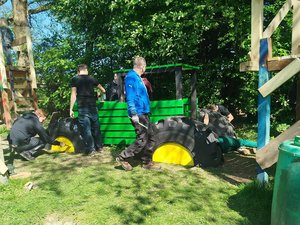 Mitarbeitende von John Deere stehen um das Holzmodell eines John Deere Traktors auf der Jugendfarm Schwarzach.