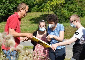 Imkermeister Hans-Jürgen Lohmüller erläutert Schülerinnen und Schülern der Johannesberg Schule die Vorgänge im Bienenstock auf dem Gelände der Johannes-Diakonie.