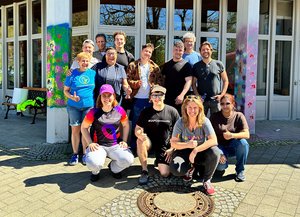 SAP-Team posiert vor der Johannesberg Schule zwischen bunt besprühten Betonsäulen.