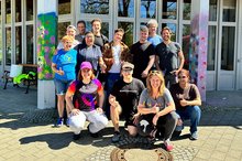 SAP-Team posiert vor der Johannesberg Schule zwischen bunt besprühten Betonsäulen.