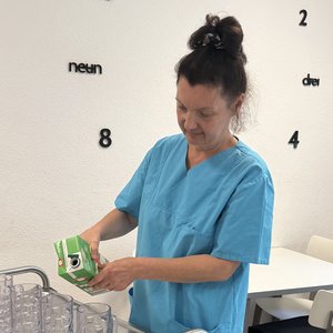 Eine Frau schenkt in einem Gemeinschaftsraum Saft in Gläser.