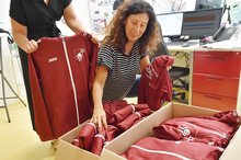 Sportkoordinatorin Claudia Geiger öffnet Kartons mit Shirts und Jacken für das Team Johannes-Diakonie..