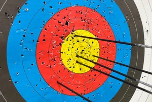 Das Bild zeigt eine Zielscheibe und darin steckende Pfeile.